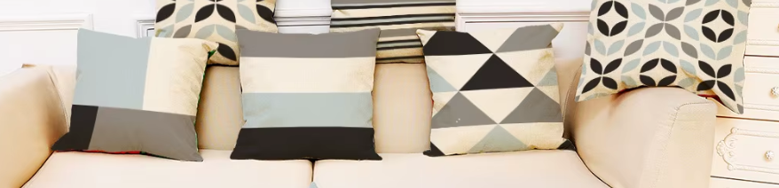 Conjunto de fundas de cojín geométricas en tonos gris, negro y azul decorando un sofá moderno