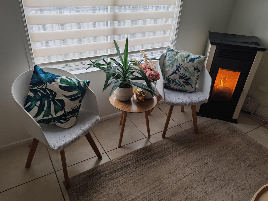 Funda de cojín hojas tropicales en sillas decorativas junto a mesa auxiliar de madera