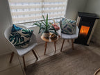Funda de cojín hojas tropicales en sillas decorativas junto a mesa auxiliar de madera