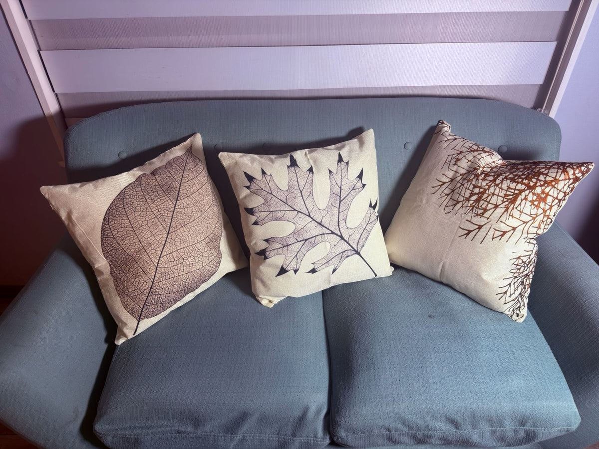 Fundas de cojín hojas otoñales con diseños de hojas botánicas decorando un sofá
