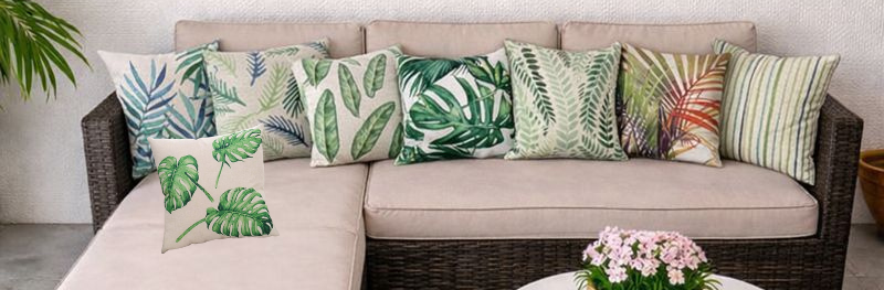 Funda de cojín hojas tropicales en sofá de terraza con mesa blanca y decoración natural
